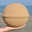 De Sand Round zee-urn in de hand, op het strand van Scheveningen met de Noordzee op de achtergrond