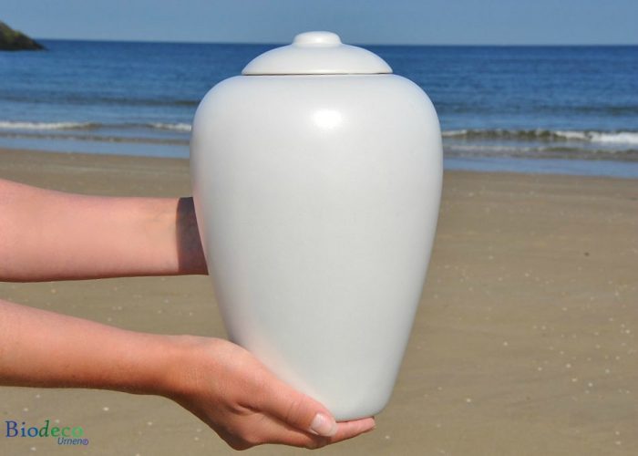 Bio-urn Classic Parel, biologisch afbreekbare urn in handen gedragen, op het strand voor de Noordzee