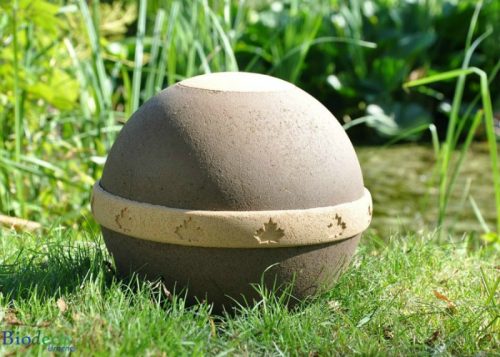 De biologisch afbreekbare eco-urn Geos, vervaardigd van gehard organisch compost, zand en mineralen, in het gras.